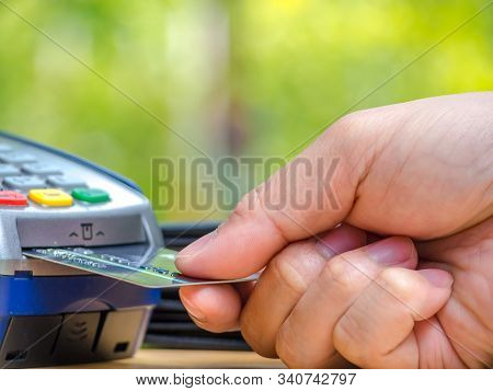 Male's Hand With Payment Credit Card Through Terminal For Shopping Retail. Payment Terminal And Cred