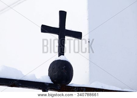 Black Steel Cross On Gate To Church In Winter