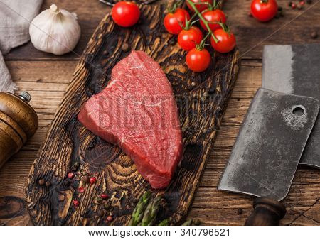 Slice Of Raw Beef Sirlion Steak On Wooden Chopping Board With Tomatoes,garlic And Asparagus Tips And