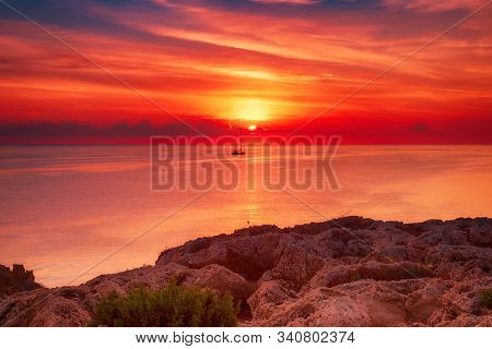 Beautiful Colorful Sunrise At The Sea With Dramatic Clouds, The Sailing Boat And Sun Shining
