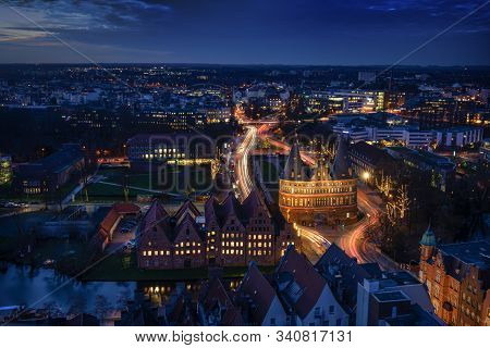 Aerial Night View Of The Illuminated City Of Luebeck, Germany In Winter With Holstentor And Historic