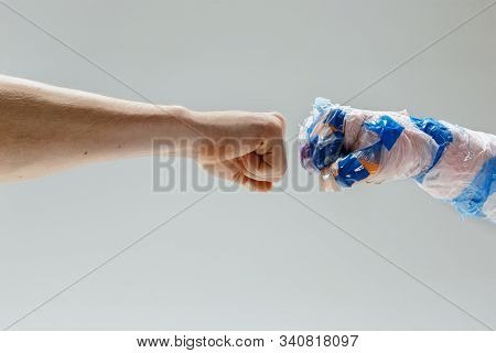 Big Plastic Hand Made Of Garbage Shaking Another Hand On White Studio Background. Polymers Overusing
