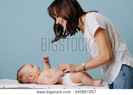 Mother Talks With Her Infant And Changes The Diaper