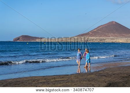 El Medano, Spain - July 9 2019: Senior Local Women Walking On Playa El Medano Beach During Sunrisee