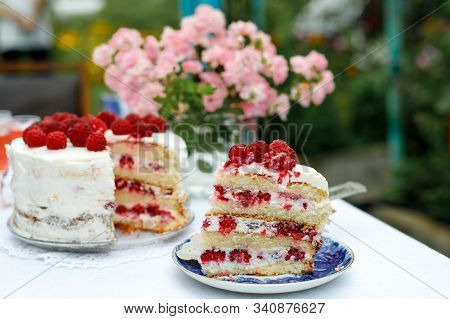 A Slice Of Homemade Raspberry Cake On A Saucer Next To A Cake On In The Summer Garden. Selective Foc