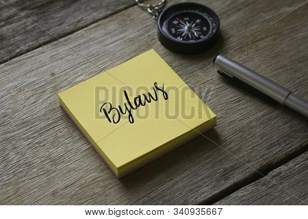 Compass,pen And Yellow Sticky Notes Written With Bylaws On Wooden Background.
