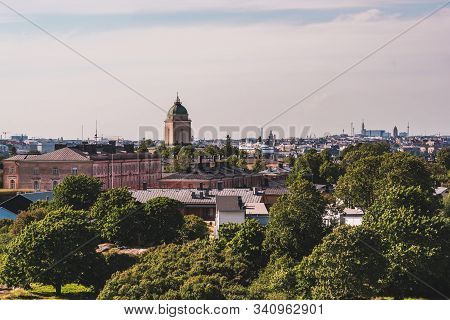 View Of Suomenlinna And Its Old Buildings And Lighthouse With Green Trees On A Summer Day With The H