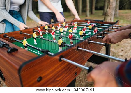 Friends Play Table Football Or Kicker Outdoors. Players And Fans Rejoice In The Victory.
