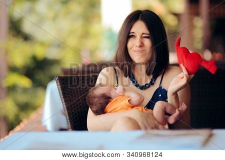 Mother Holding Toy Calming Her Crying Baby In A Restaurant