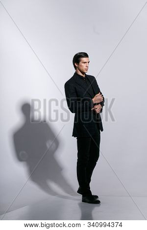 Man In Elegant Suit, Poses With Attitudine, Isoalted On A White Background. Touching His Button On J