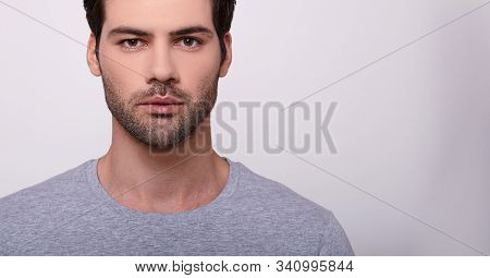 Close-up The Face Of A Beautiful Young Charismatic Confident Guy In A Gray T-shirt. A Young Man With