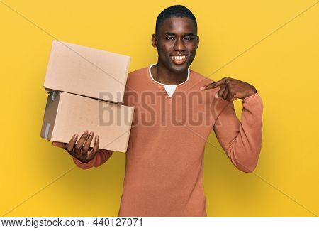 Young african american man holding delivery package pointing finger to one self smiling happy and proud 