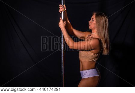 Girl Athlete Performs Exercises Dancing On A Pole On The Stage In The Dark. Poledance Sexy Woman On