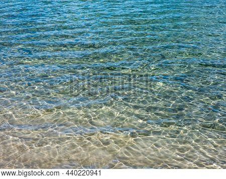 Texture Of Beautiful, Crystal Clear Light Blue And Turquoise Transparent Water With Fine White Sand 