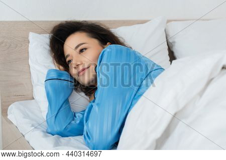 Brunette Woman In Blue Pajamas Lying On Bed