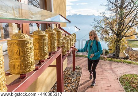 Adult Woman Wearing Sunglasses Looking At The Prayer Wheels Of A Tibetan Buddhist Temple At Mont Pel