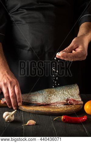 The Chef Prepares Fresh Fish Sprinkling Salt. Preparing To Cook Fish Food. Working Environment In Th