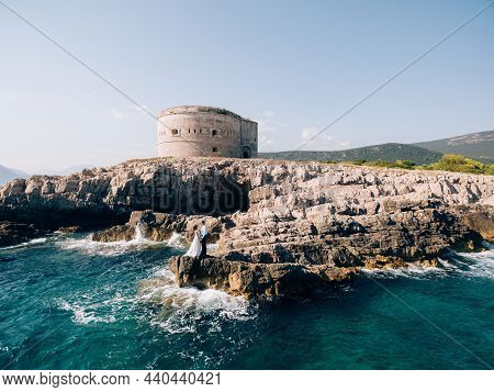 Bride And Groom Stand On The Rocks Against The Background Of The Arza Fortress