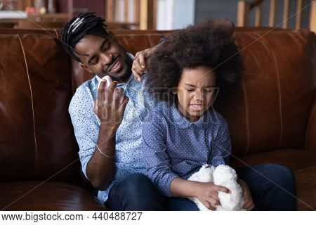 Smiling African Ethnic Father Detangling Hair Of Small Daughter.