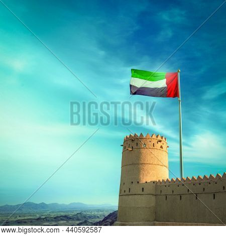 Flag of UAE flying on the fort against blue sky background. National Day marks the UAE's formal nationalisation in 1971.