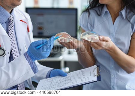 Close-up Of Professional Doctor Explain Difference Between Breast Implants To Client. Medical Worker