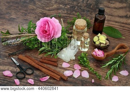 Preparing a pagan love potion with witches bundle of herbs and rose flower, lovespoon with petals, tincture bottle, cinnamon and ginger spices and quartz crystal. Romantic dating concept.