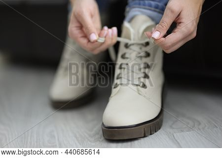 Close-up Of Woman Put Her White Boots On And Tie Laces Before Going Out. Fashion Beige Leather Winte