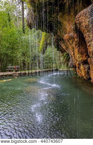 Calcareous Crystalline Water Falling Into A Basin From A Rock Formation Covered With Green Moss, Kal