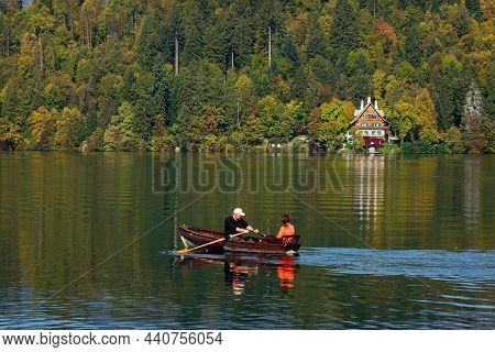BLED, SLOVENIA - OCTOBER 17, 2021: Tourists on a rowing boat in front of Blejsko ostrvo, bled island, on Bled lake or Blejsko Jezero                               