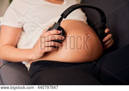 Caucasian Pregnant Woman Placing Headphones On Belly
