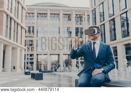 Smiling Businessman Sitting On Bench In Town Square With Vr Glasses On, Viewing Information In Virtu