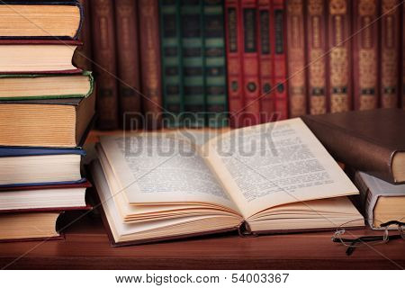 Pile of books with reading glasses on desk