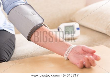 Women's hand with blood pressure monitor cuff