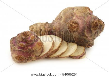 bunch of topinambur roots (helianthus tuberosus) and a cut one on a white background