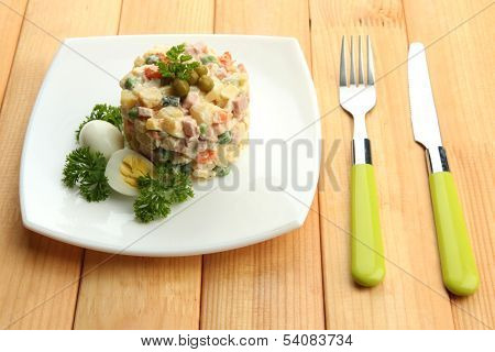 Russian traditional salad Olivier, on wooden background