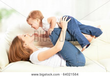 Happy Family. Mother And Baby Daughter Plays, Hugging, Kissing  On The Sofa