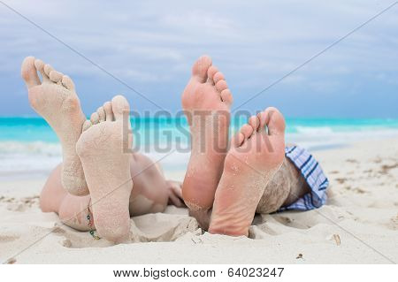 Close up male and female feet on white sand beach