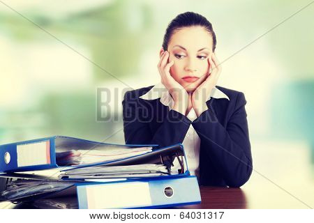 Sad woman with ringbinders sitting at the desk. Tired and exhousted business woman. 
