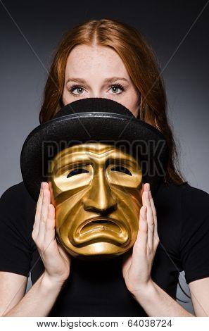Redhead woman in hat  iwith mask  in hat in hypocrisy consept against grey background