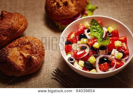 Salad With Fresh Vegetables And Burger And Buns In The Background. On Rustic Tissue.