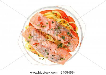 fresh fried natural pink salmon on italian traditional tagliatelle backed with tomato and vegetables isolated over white background