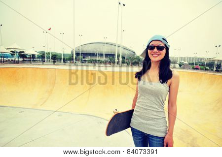 young woamn skateboarder hold a skateboard at skatepark