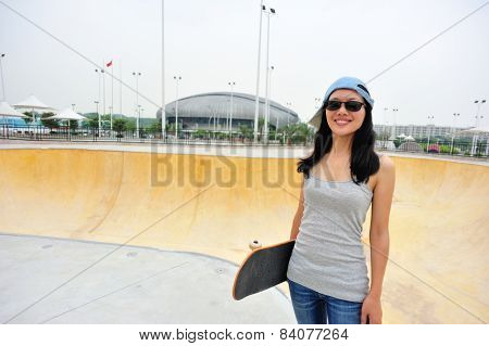 young woamn skateboarder hold a skateboard at skatepark