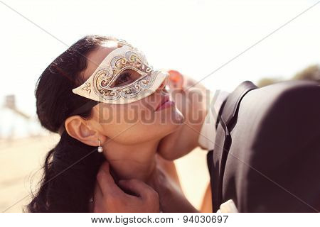 Groom Kissing His Bride. Bride Wearing Venezian Mask