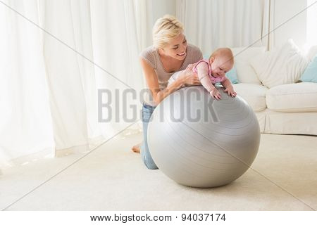 Happy mother with her baby girl in the exercice ball at home in the living room
