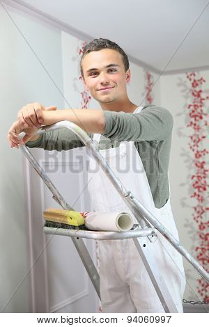 Young apprentice learning how to put wallpaper up on wall