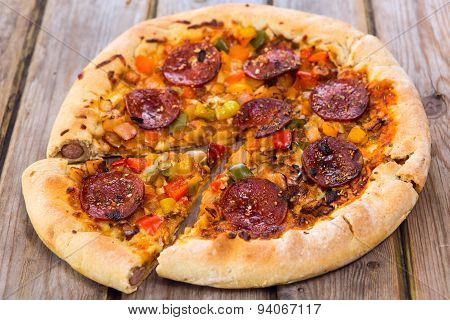 Delicious Baked Salami Pizza Served On Rustic Wooden Table