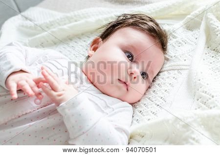 Cute Newborn Baby Girl In Romper Suit Lying On Woolen Blanket