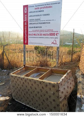 Alora Spain - September 27 2016 - Settee dumped underneath warning sign regarding fly tipping