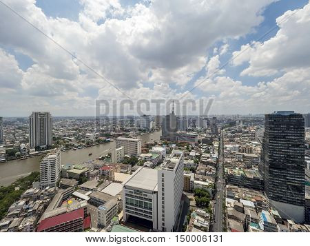 Cityscape and modern building near the river in the afternoon at Chao Phraya River in Bangkok Thailand under blue sky and cloud